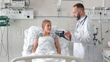 <strong>男医生</strong>在病床上与女病人交谈。 带剪贴板和x光照片的<strong>微笑医生</strong>